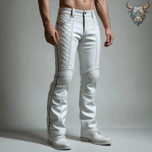 Op de afbeelding: Witte leren broek met gewatteerde details op de dijen en knieën, met zwarte stiksels en een ritssluiting. De broek wordt gecombineerd met witte schoenen. De stijl is strak en modern.