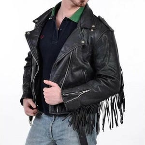 Puede incluir: Chaqueta de cuero negra estilo motero con flecos. La chaqueta tiene cierre de cremallera asimétrico, cuello con solapas y herrajes plateados. Las mangas tienen puños con cremallera. Estilo motero clásico.