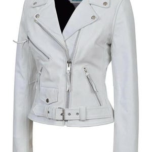 May include: White leather motorcycle jacket with a notched collar, asymmetrical zip closure, and multiple zippered pockets. Features a belt at the waist and silver hardware. The jacket has the text "Carrie Hoxy" on the inside.