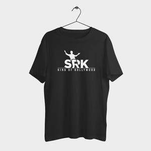 Puede incluir: Camiseta negra con un gráfico blanco que presenta las letras "SRK" sobre las palabras "KING OF BOLLYWOOD" y una silueta de una persona con los brazos extendidos. La camiseta está colgada de una percha negra.