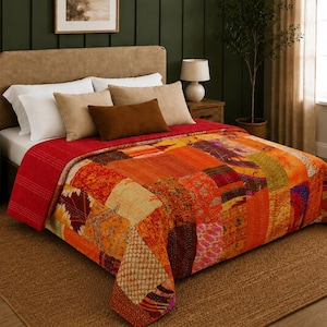 Può includere: Un letto con una trapunta patchwork nei toni dell'arancione, del rosso e del giallo. La trapunta presenta una varietà di motivi e trame. Il letto ha cuscini bianchi, cuscini beige e un cuscino marrone. Il letto è in una stanza con una parete verde e un tappeto marrone.