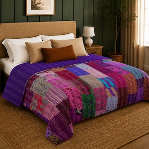Puede incluir: Una colcha de patchwork que presenta una vibrante variedad de cuadrados de tela en tonos morado, magenta, rosa y turquesa con intrincados patrones de costura. La colcha cubre una cama, mostrando una mezcla de estampados florales y geométricos.