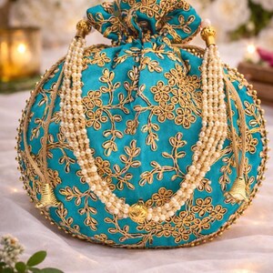 Peut inclure: Sac rond à cordon de serrage de couleur turquoise avec broderie florale dorée. Le sac est orné d'une bandoulière perlée et de glands dorés. Le design est orné et élégant, adapté aux occasions spéciales.