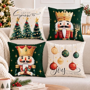 May include: Four square throw pillows featuring Christmas themes. Two pillows are cream-colored with 'Let It Snow' and 'Joy to the World' text, decorated with pine trees and ornaments. Two dark green pillows feature a nutcracker soldier design.