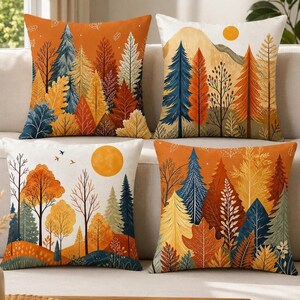 Könnte beinhalten: Ein Set aus vier quadratischen Zierkissen mit herbstlichen Waldlandschaften. Die Designs zeigen verschiedene Bäume in Orange-, Gelb-, Blau- und Brauntönen sowie Berge, Sonnen und Vögel auf weißem und orangefarbenem Hintergrund.