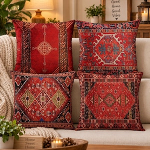 May include: A set of four square throw pillows featuring intricate red, black, and gold geometric patterns. Each pillow displays a unique, detailed design inspired by traditional rug motifs, with rich crimson tones and contrasting dark borders.