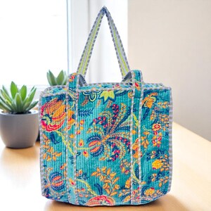 Blue printed floral velvet tote bag placed on a white sofa.