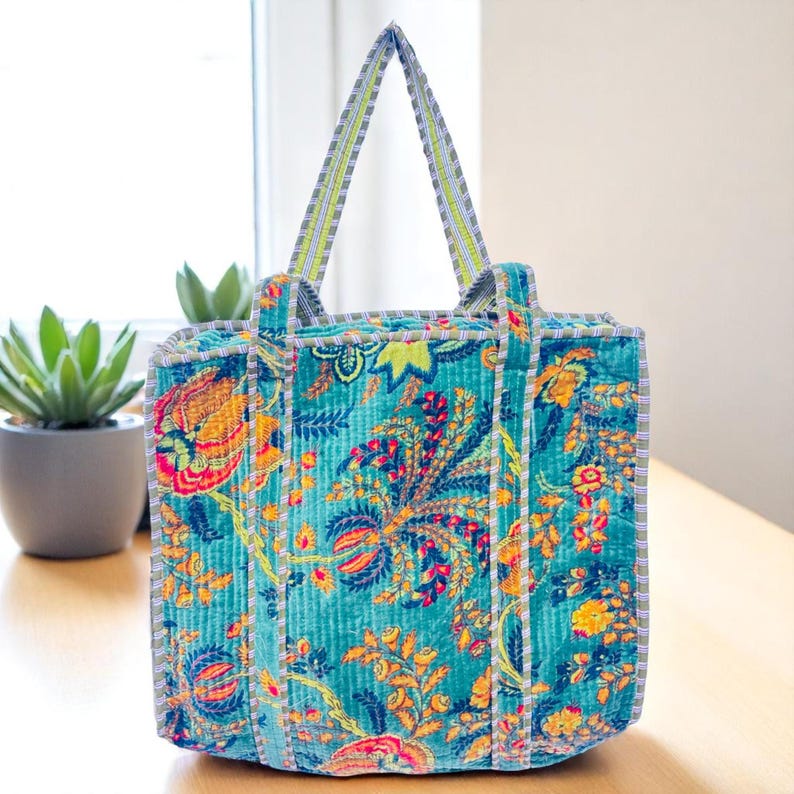 Blue printed floral velvet tote bag placed on a white sofa.