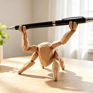 May include: A light-colored wooden figure with a faceted, geometric design, posed in a crouched position with arms raised overhead. The figure holds a sleek, black ballpoint pen horizontally between its hands, serving as a functional desk accessory.