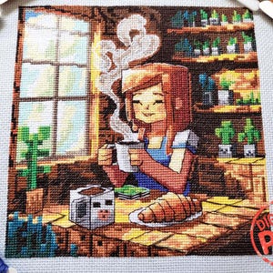Puede incluir: Patrón de punto de cruz que presenta una ilustración pixelada de una persona disfrutando de café y un cruasán. La escena incluye una ventana, una mesa y una estantería con plantas. La imagen tiene una paleta de colores cálidos y el texto "Digital PDF Pattern".