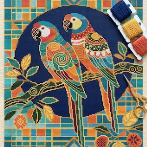 May include: A cross-stitch embroidery project featuring two parrots perched on a branch against a dark blue circular background. The parrots are decorated with colorful geometric and spiral patterns. Three spools of embroidery floss and gold scissors.