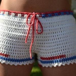 May include: White crochet shorts with red, blue, and white trim. The shorts have a drawstring closure.