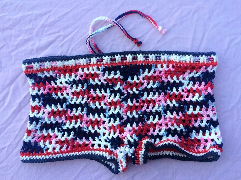 May include: Crocheted shorts in a red, white, and blue color pattern. The shorts have a tie at the top.