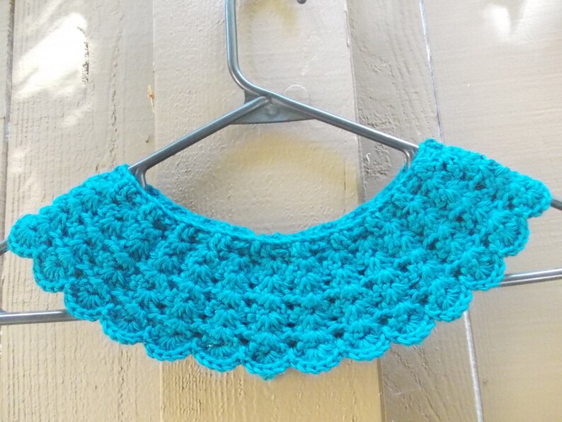 May include: A teal blue crocheted collar with a scalloped edge.