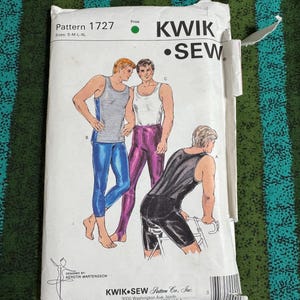 May include: A Kwik Sew pattern envelope 1727 for sizes S-M-L-XL featuring illustrations of three individuals wearing tank tops and leggings or shorts. The white paper envelope includes the brand name, pattern number, and company address details.