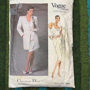 May include: Vintage Vogue Patterns sewing pattern featuring a Christian Dior design. The pattern packet shows illustrations of a woman in a white suit and dress. The Vogue Patterns logo and "Paris Original" are visible.