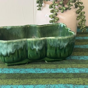 May include: A rectangular ceramic planter with a scalloped edge and a glossy finish. The vessel features a deep forest green glaze that transitions into a lighter, mottled mint green drip pattern along the upper rim and vertical ridges.