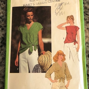 May include: Simplicity sewing pattern number 8587 for a blouse with a tie front. The pattern includes three different views: a green blouse with a white skirt, a red blouse with a white skirt, and a beige blouse with white shorts. The pattern is for size 10 miss.