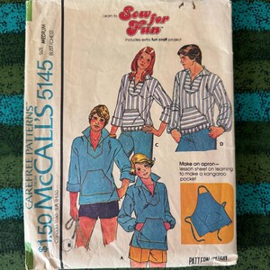 May include: Vintage McCall's sewing pattern 5145. The pattern features illustrations of tops with kangaroo pockets. The package includes the text "Sew for Fun" and "Includes extra fun craft project". The pattern is for a medium size.