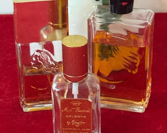 Puede incluir: Tres frascos de colonia vintage con detalles rojos y dorados. Los frascos son rectangulares y cuadrados, con tapones dorados y negros. Las etiquetas dicen "Most Precious Cologne by Roger & Gallet". Los frascos están llenos de líquido color ámbar.