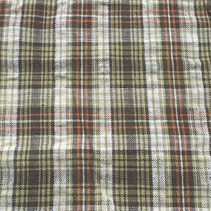 May include: A woven fabric featuring a plaid pattern with vertical and horizontal stripes in shades of dark brown, olive green, white, and thin accent lines of bright orange. The textile has a visible cross-hatched texture throughout the surface.