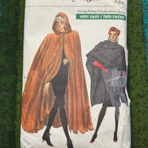May include: A Very Easy Very Vogue sewing pattern packet. The packet features illustrations of two women wearing capes. The text on the packet reads "Very Easy" and "Très Facile". The pattern size is P-S-M.