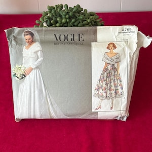 Peut inclure: Un patron de couture vintage Vogue Bridal Original. L'enveloppe du patron présente des illustrations de deux robes de mariée. L'enveloppe est grise avec le logo Vogue et le numéro de patron 2768.