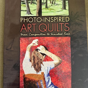 May include: A book titled "Photo-Inspired Art Quilts" with a cover featuring a forest scene and a person arranging their hair. The book includes the text "From Composition to Finished Piece" and "Leni Levenson Wiener". A DVD is included.