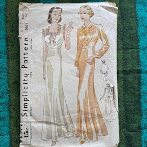 Op de afbeelding: Vintage Simplicity naaipatroon met illustraties van twee lange jurken. Het patroon bevat de tekst "Simplicity Pattern" en "New York, London, Paris". De prijs is gemarkeerd als 15c. De borstomvang is 91 cm.