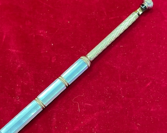 May include: A silver and white pencil with a decorative twist pattern. The pencil has a white, opaque, cylindrical body with three gold bands. The top of the pencil is silver and has a small, round, black knob.