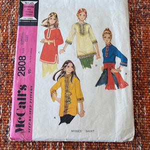 May include: A vintage McCall's 2808 sewing pattern for Misses' shirts. The pattern shows illustrations of four shirt designs in red, yellow, and blue. The pattern size is medium, 12-14. The text says 'It's Young Fashion'.