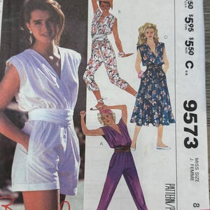 May include: A sewing pattern for a jumpsuit with three different styles. The pattern is for size 8 and is called McCall's 9573. The pattern is for a jumpsuit with a V-neck and a wrap-style waist.