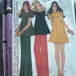 Può includere: Modello di cucito vintage con illustrazioni di tre donne in abiti e pantaloni. Il modello include un abito floreale verde, un abito nero con pantaloni rossi e un abito giallo. Il testo sul modello recita "Abito o top e pantaloni da donna".