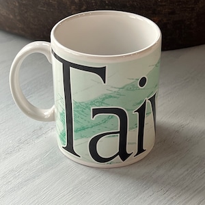 May include: White ceramic mug with a green and white marbled design and the word "Fair" in black lettering.