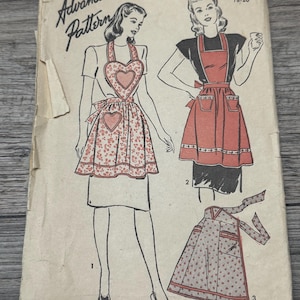 Puede incluir: Sobre de patrón Advance vintage con diseños de delantales. Las ilustraciones muestran delantales con petos en forma de corazón y detalles de bolsillo. El sobre está envejecido, con el texto "Advance Pattern" y el precio "15¢" visibles.