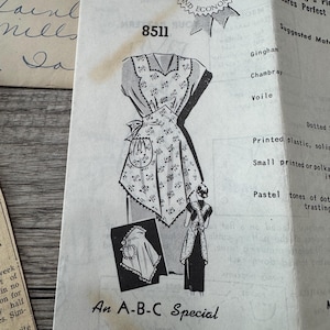 May include: Vintage sewing pattern for two aprons, featuring a detailed illustration of the apron design. The pattern includes the text "An A-B-C Special" and "TWO APRONS". The pattern is printed on aged paper with additional text and a "1st Prize" seal.