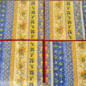 May include: Four rectangular fabric placemats featuring a repeating vertical striped pattern. The design includes bands of yellow with orange floral motifs, blue with green grape leaves and white grapes, and thin columns of small blue plums on yellow.