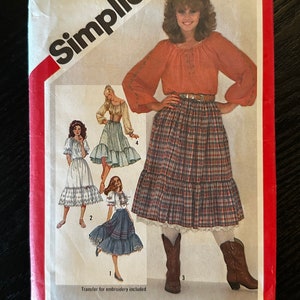 May include: Simplicity sewing pattern number 5283 for a size 12 miss. The pattern includes instructions for making a blouse and a skirt. The skirt is a tiered skirt with a plaid pattern. The blouse is a long-sleeved blouse with a gathered neckline. The pattern includes a transfer for embroidery.
