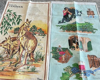 Puede incluir: Dos paños de cocina, uno con una familia de canguros y un poema sobre Australia, el otro con una escena de viñedo y el texto "Australian Wineries".