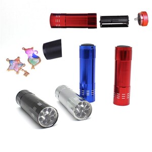May include: Four flashlights with different colored bodies: red, blue, silver, and black. Each flashlight has a clear lens with multiple LED lights visible inside. The flashlights are on a white background.