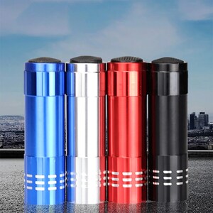 May include: Four small flashlights in different colors: blue, silver, red, and black. Each flashlight has a textured grip and a small, round button on the top.
