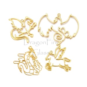 May include: Four gold-colored metal charms in the shapes of mythical creatures. The charms include a dragon, a winged dragon, a pegasus, and a creature with large wings. The charms are on a white background.