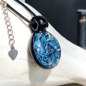Black glass pendant containing pet ashes on a black adjustable cord. Made to order by DragonFire Glass