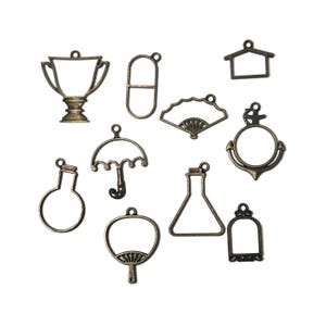 May include: A collection of bronze-colored metal charms in various shapes, including a trophy, a pill, a fan, an anchor, a house, a flask, an umbrella, a test tube, a hand fan, and a decorative frame. These charms are ideal for jewelry making or crafting projects.
