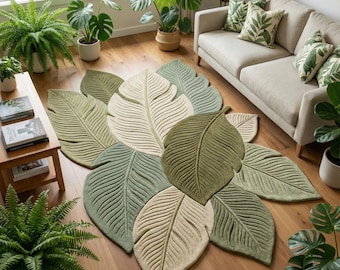 May include: A large area rug shaped like a cluster of overlapping tropical leaves in shades of sage green, olive green, and cream. The rug features detailed carved veins on each leaf segment, creating a textured surface that mimics natural foliage.