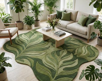 May include: A green leaf-shaped rug with varying shades of green, creating a textured, three-dimensional effect. The rug is the focal point of a living room, surrounded by potted plants, a beige sofa, and a light-colored wooden coffee table.