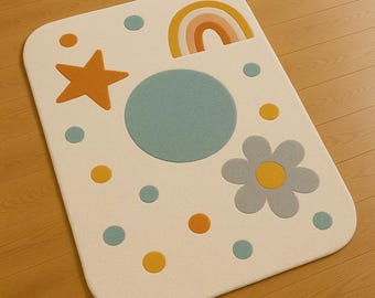 May include: A rectangular off-white rug with a whimsical design. It features a star, rainbow, flower, and various-sized circles in shades of orange, yellow, and blue. The rug is placed on a wooden floor.