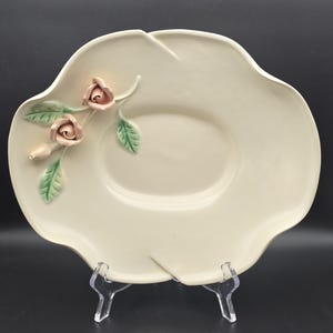 May include: A white ceramic serving dish with a raised design of pink roses and green leaves.
