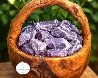 May include: A wooden basket filled with rough, lavender-colored stones. The basket has a curved handle and is made of light brown wood. The text "MindRefreshingStone" is visible on the basket. The stones appear to be amethyst.