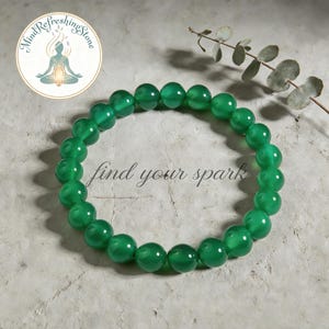 May include: A green beaded bracelet with the text "find your spark". The bracelet is made of round, polished beads. The image also includes a logo with the text "Mind Refreshing Stone".